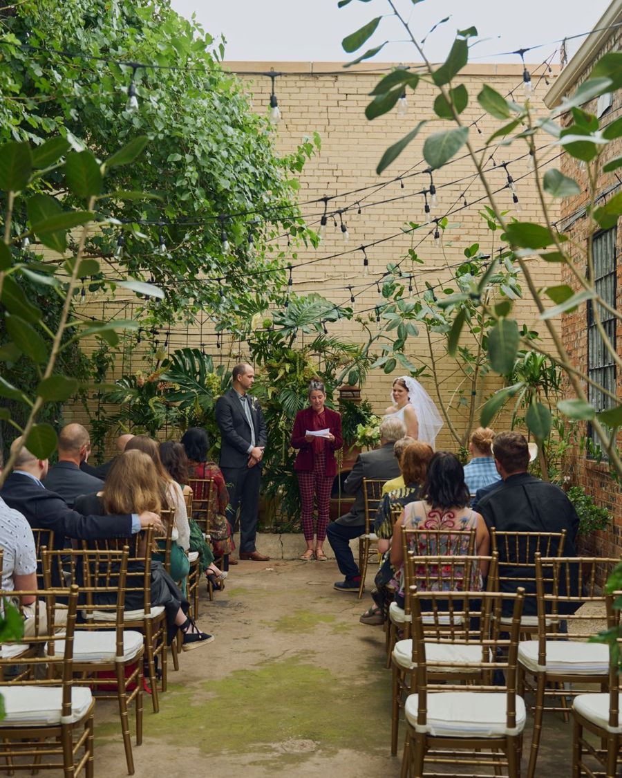 A wedding ceremony on the private patio, guests seated under string lights and climbing vines