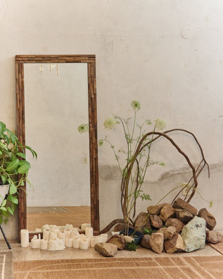 The salon: white plaster walls, an antique mirror, candles and a branch arrangement